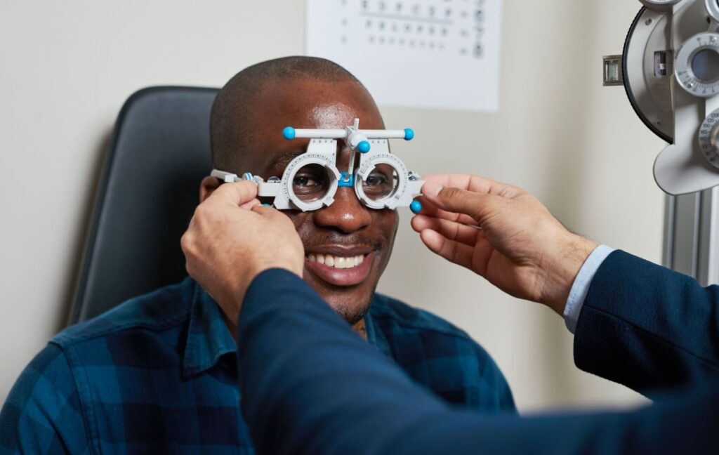 A person sits in a chair while their optometrist measures their face for a custom glasses fit.