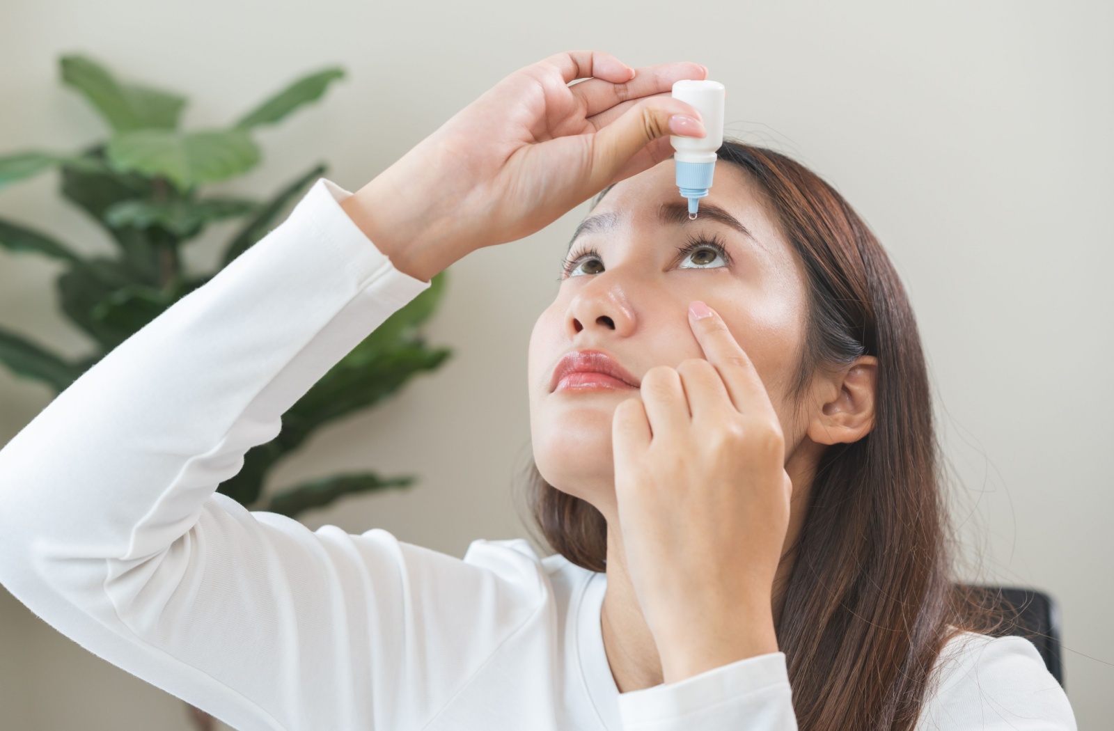 Portrait of a young person using eye drops.