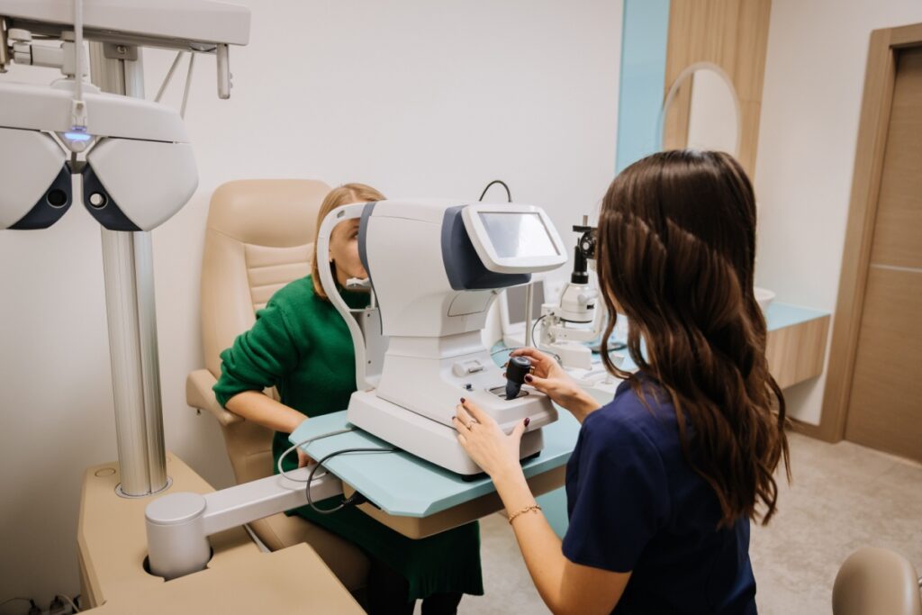 Older woman being assessed by an optometrist using an autorefractor.